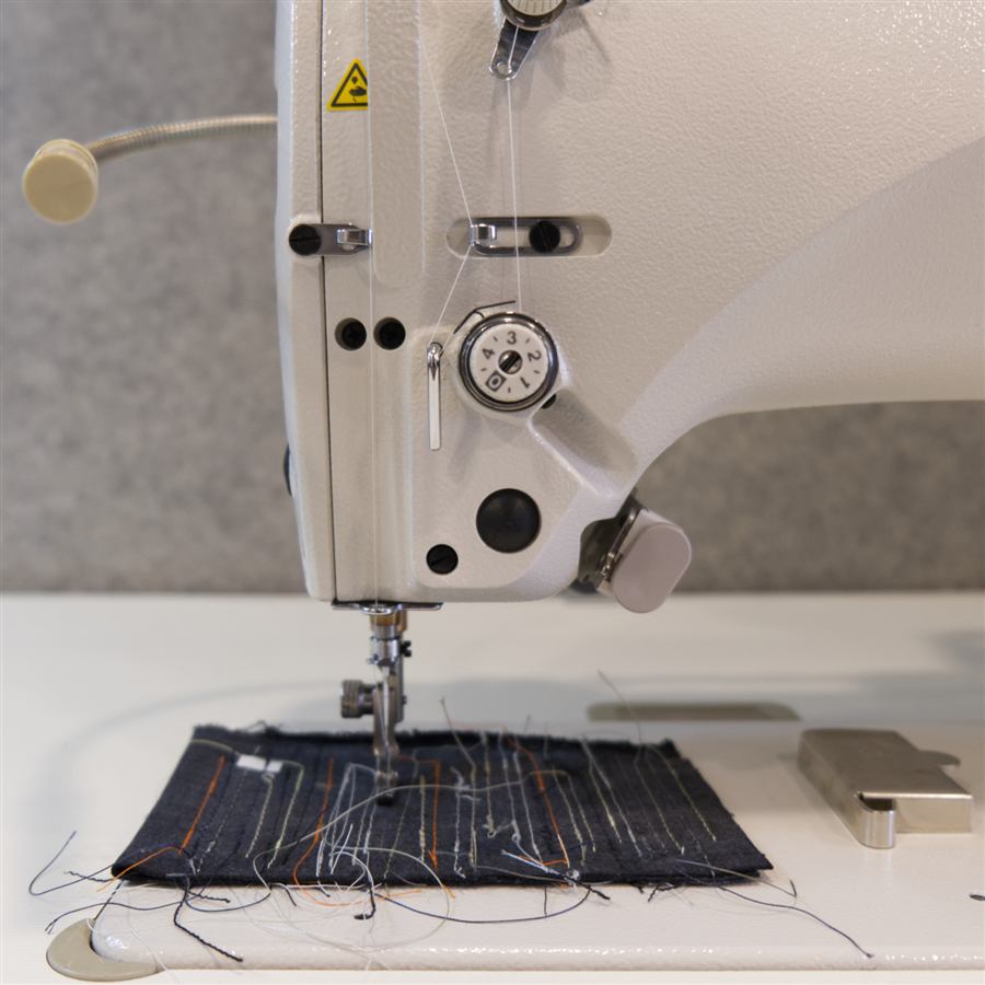 Nahaufnahme der Nähmaschine beim Vernähen von Jeansstoff