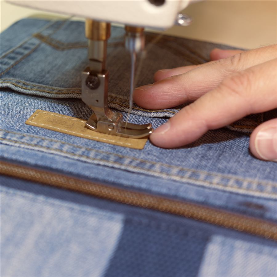 Nahaufnahme beim Nähen von Jeansstoff an der Nähmaschine