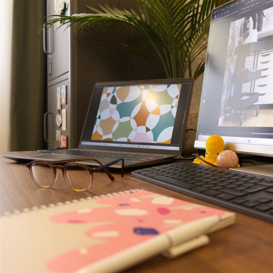 Laptop mit eigenem Musterdesign und Skizzenbuch auf dem Schreibtisch